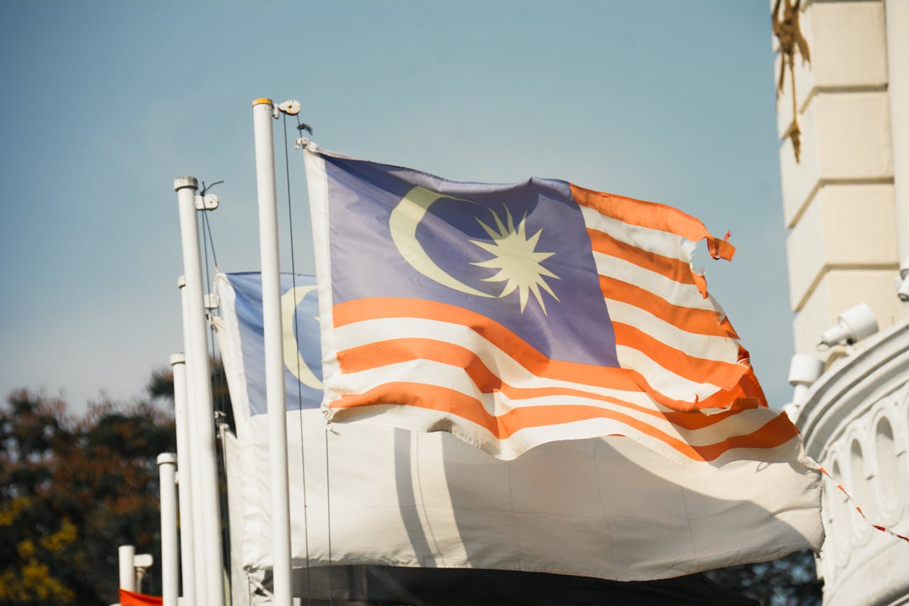 expertise-01 A vibrant Malaysian flag waving against a clear blue sky symbolizes national pride and patriotism.
